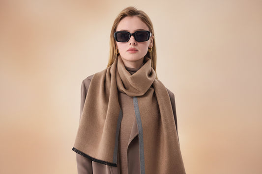 Woman wearing a camel and grey silk scarf styled as a winter wrap with a neutral coat