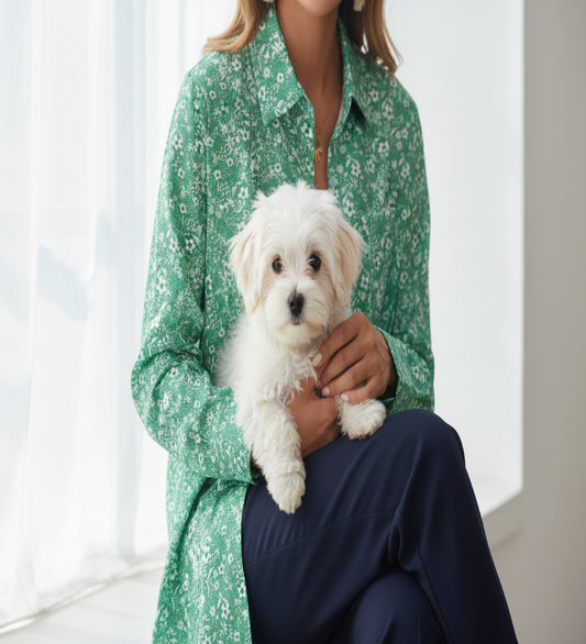 Woman in her 30s - wearing a loose-fitting top by the window with her dog