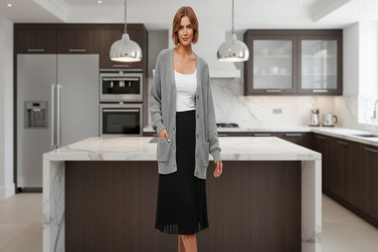 A woman poses in front of a luxury kitchen wearing the Qualfort Women's 100% Cotton Oversized Cardigan (Gray) styled with a black skirt and white top.