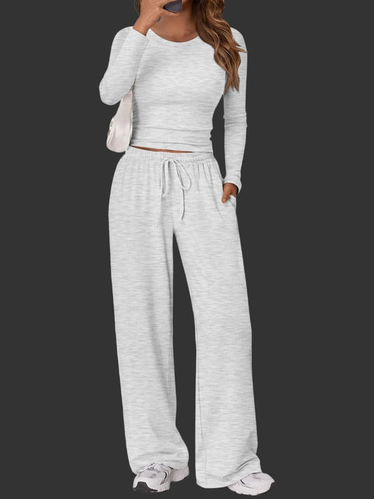 Full-length view of a woman wearing Trendy Queen oatmeal grey 2-piece lounge set featuring a long sleeve top and wide-leg drawstring pants.